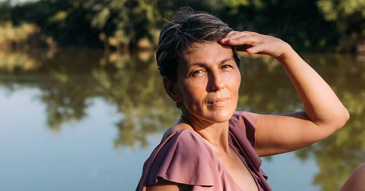 Post-menopausal woman sitting by the river.