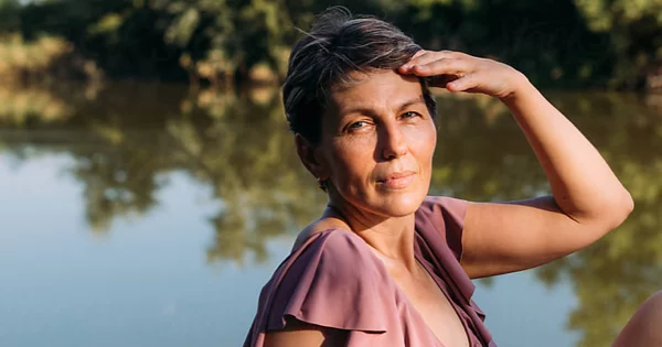 Post-menopausal woman sitting by the river.