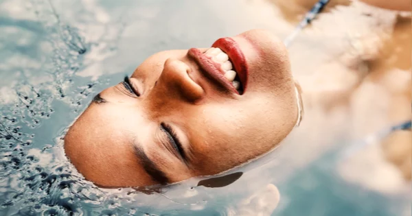 woman smiling cooling off back of her head in a pool