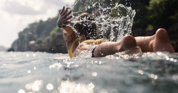 View of a woman wearing a bathing suit and surfing.