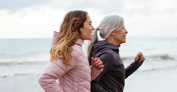 Perimenopausal woman and menopausal woman running on beach with bladder control