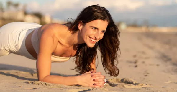 Healthy middle aged woman doing yoga on the beach and smiling.
