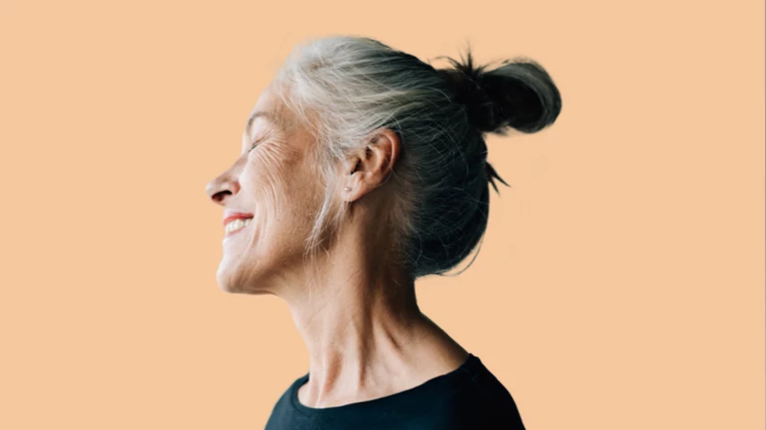 Healthy middle aged woman doing yoga on the beach and smiling.
